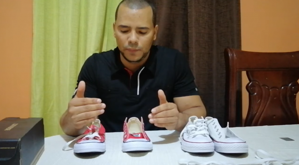Youtuber explaining how to identify original converse with 4 pairs of converse on the table.