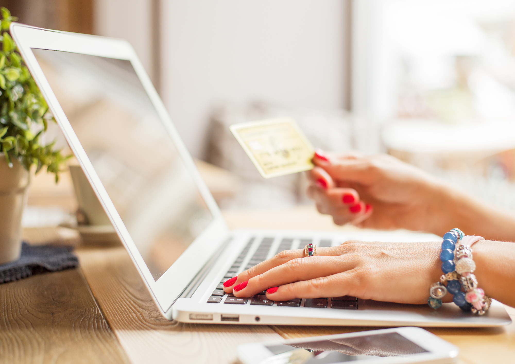 woman's hands touching laptop with credit card in hand