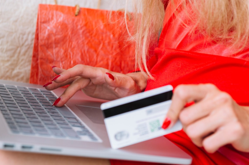 closeup woman using laptop while holding a card