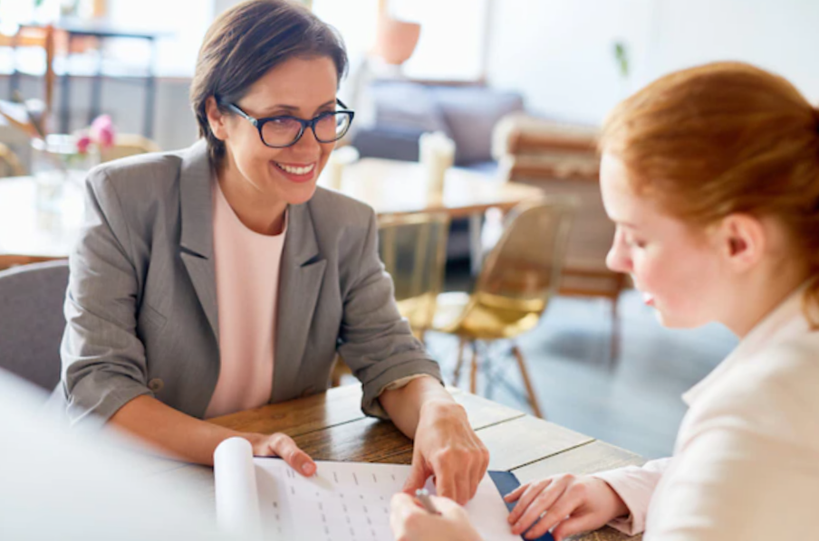 female manager showing how to fill out job application to a young girl