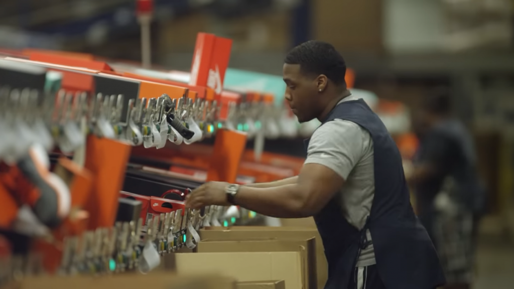 Warehouse worker arranging boxes of Nike shoes.