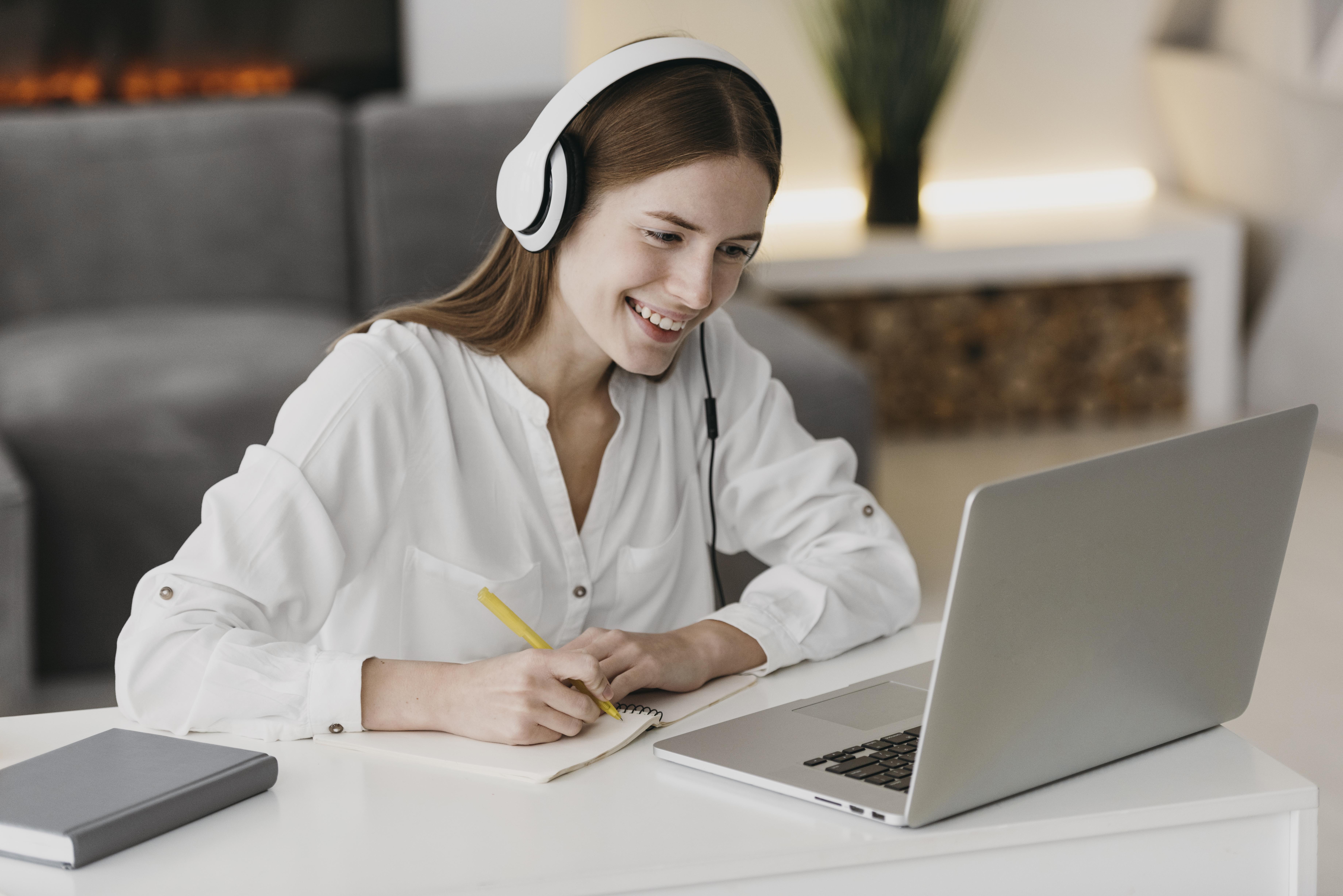 Woman sitting at desk with headphones in front of a laptop