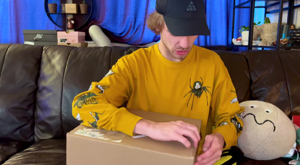 youtuber in yellow shirt checking ssense packaging