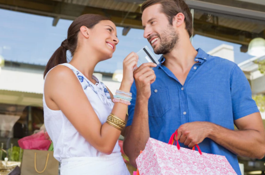 young happy couple looking each other while handing a credit card
