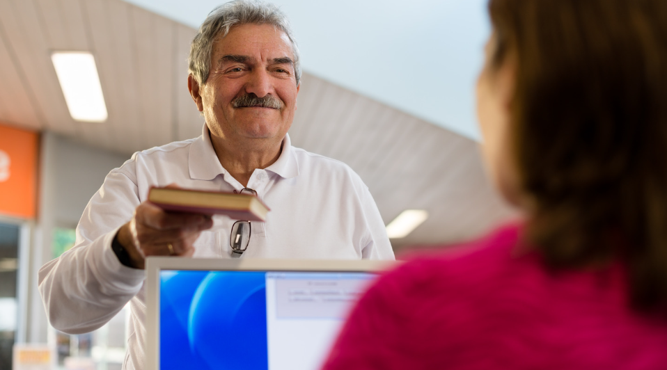 girl and senior man returning book in library