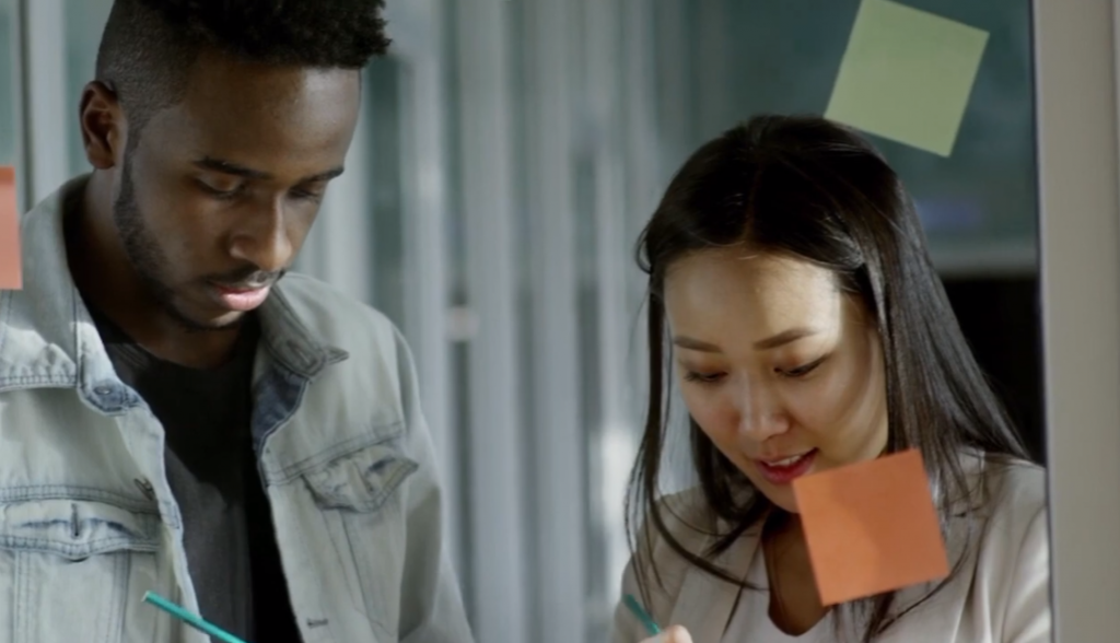 Black man and Asian woman using sticky notes
