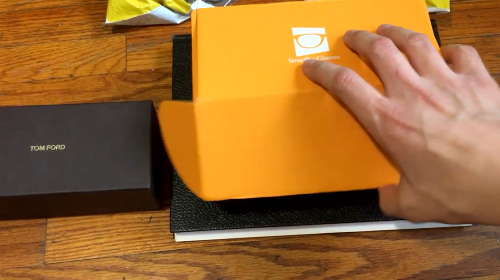 man's hand opening a smart buy glasses orange box