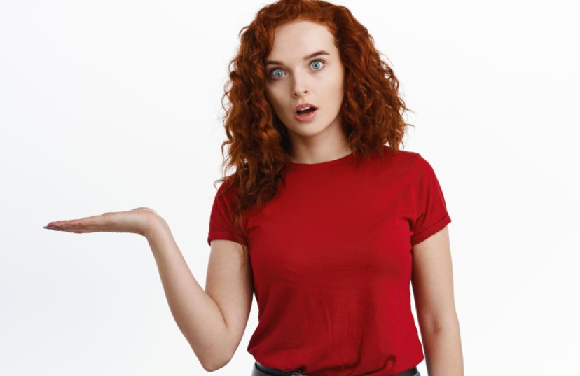 Surprised girl holding on palm looking amazed at camera white background