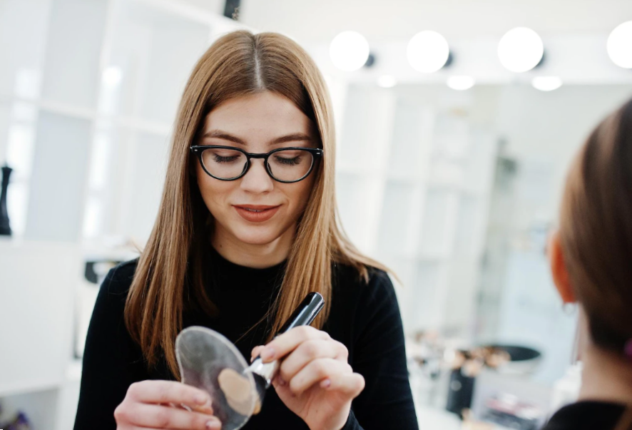 young female make up artist taking foundation with her brush from a mixing palette