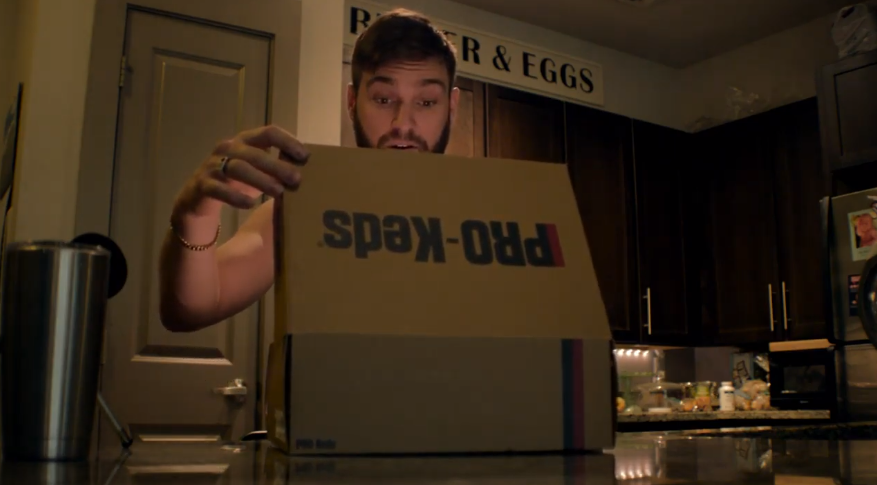 men opening a pro-keds box with an impressed face