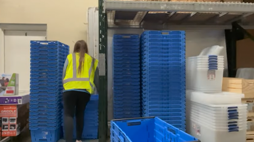 Walmart worker wearing a green vest arranging shopping baskets