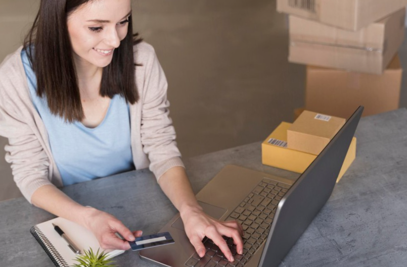 High angle of woman working with laptop and boxes
