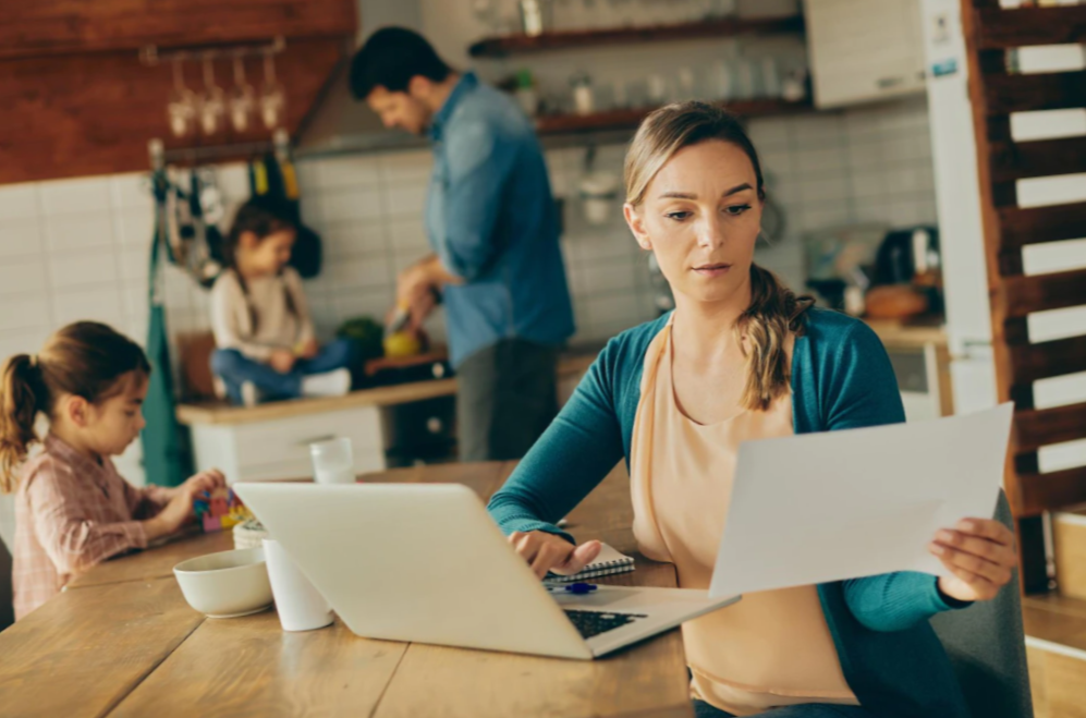 woman reading a document while using laptop 