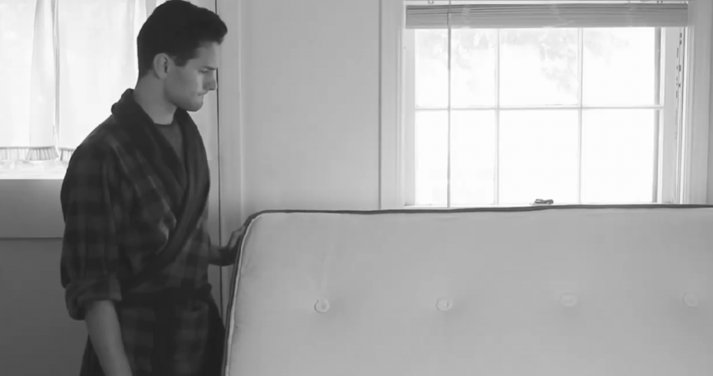 black and white photo of man with mattress