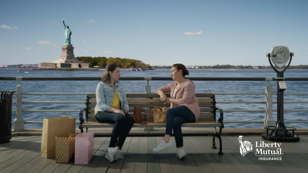 Two women talking on a bench with the statue of liberty in landscape