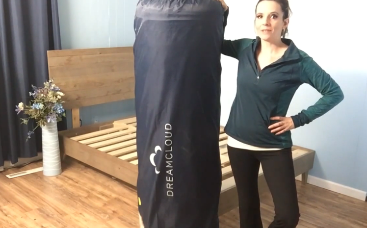women holding a dreamcloud mattress on its package
